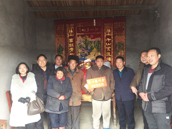 商會會長熊桂祥（左二）、監事會主席李榮杰（右二）和萬盛合作社董事長張世和（左一）、總經理王喜本（右一）帶著慰問團正在慰問張澤俊全家（圖中），并與他們合影留念