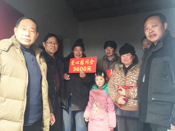 商會愛心尉問團正在慰問張澤家全家（圖中），并與他們合影留念