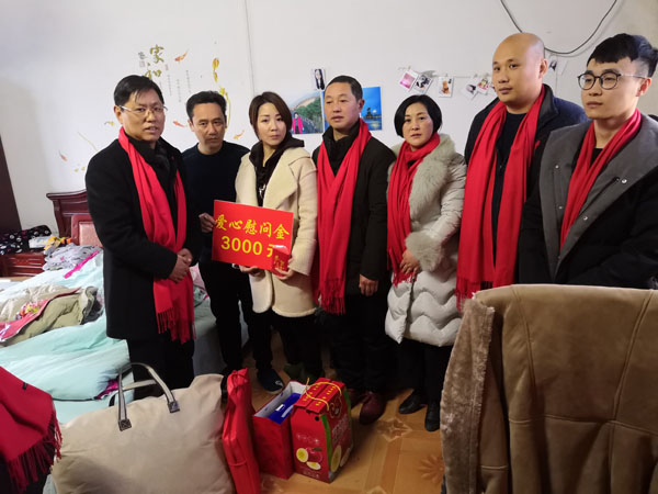 熊桂祥會長(左一)、徐敏秘書長（右三）、許生永經理（右二）、謝炳浩總助（右一）給楊白林特困戶家送上慰問金和慰問物品，圖為他們與長年臥病在床的楊白林夫婦的一雙整日侍奉兒女（左二、左三）及霍邱縣河口鎮領導（中）合影留念